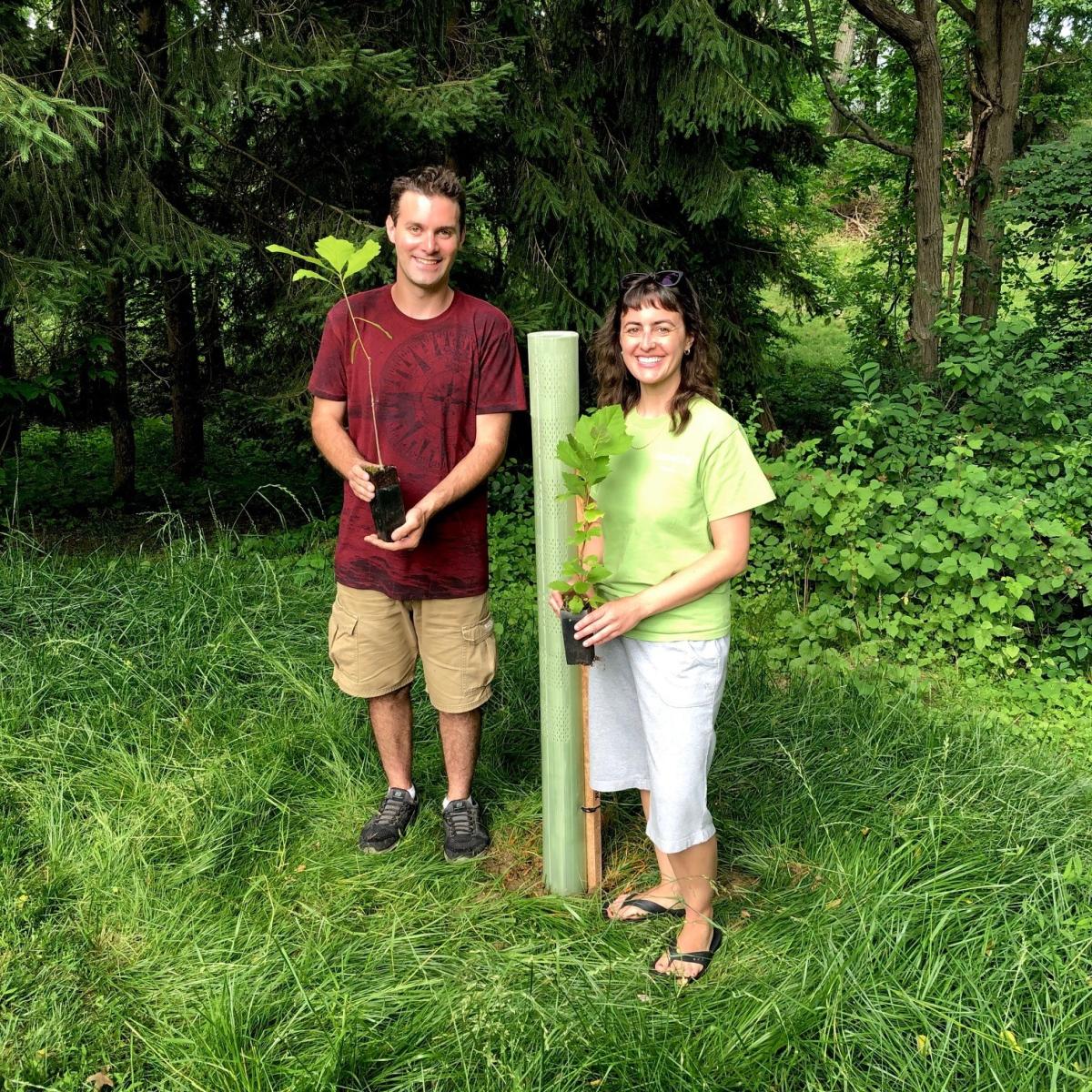 man and women holding saplings and smiling 