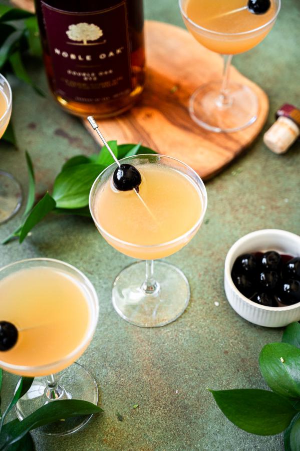 Shows cocktail in a coup glass garnished with a cherry 