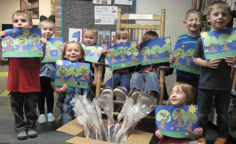 Group of Elementary School kids show off pictures of trees they crafted.