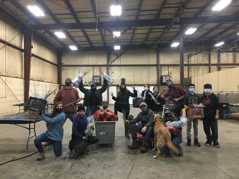 Group poses with trees in warehouse