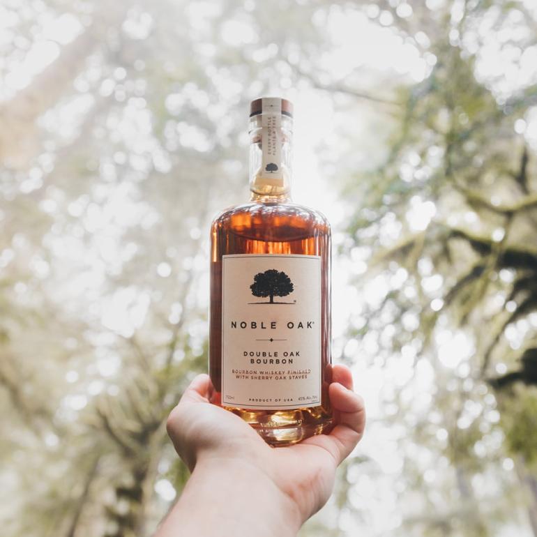 Shows someone holding a bottle under a tree canopy
